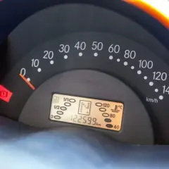 Cruscotto auto con tachimetro, indicatore carburante e spia freno a mano accesa. Chilometraggio 122599 km.