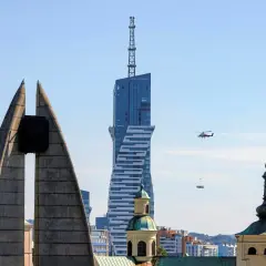 Widok na najwyższy budynek mieszkalny w Polsce, z helikopterem dostarczającym ładunek.