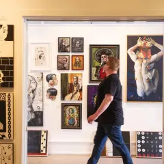 A man walks through a doorway into a vibrant display of art, showcasing diverse styles at Santa Fe art galleries.
