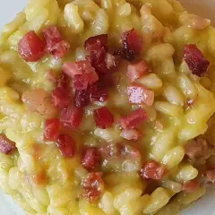 Un cremoso risotto con asparagi e pancetta croccante, un piatto ricco di sapore e profumo.
