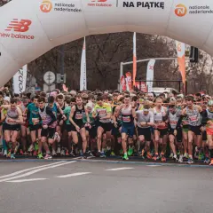 Start biegu na 10 km. Tłum biegaczy pod łukiem startowym New Balance, gotowi do rywalizacji.