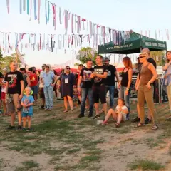 Ludzie na festiwalu trzcianka, w tle kolorowe wstążki i namioty.