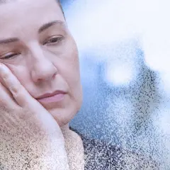Zmęczona kobieta z dłonią na policzku, symbolizująca mgłę covidową i długotrwałe skutki choroby.