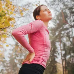 Femme en tenue de sport, le dos douloureux, se tenant la hanche. Le sport peut être mauvais pour le dos.