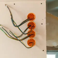Instalacja elektryczna w domku drewnianym w trakcie prac. Widoczne puszki instalacyjne i przewody.