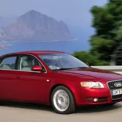 Czerwone Audi 2.0 TDI sunie po drodze z widokiem na morze i góry.