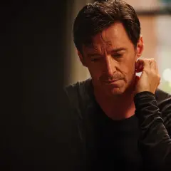 Hugh Jackman w filmie "The Son" zamyślony, z dłonią przy uchu.
