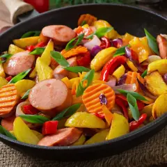 Smażona kiełbasa z ziemniakami i warzywami na patelni. Pytanie, czy można gotować zamrożoną kiełbasę, jest tu nieistotne, bo danie wygląda apetycznie!