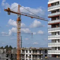 Plac budowy z dźwigiem i nowym budynkiem mieszkalnym. To obrazuje, co to jest lex deweloper – ułatwienia dla budownictwa mieszkaniowego.