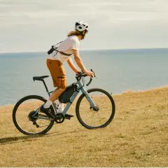 Mężczyzna w kasku jedzie na rowerze gravelowym Van Rysel wzdłuż wybrzeża.