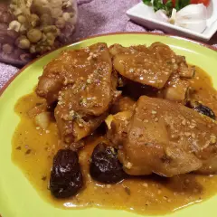 Pies de cerdo a la catalana, un plato tradicional con trozos de cerdo en una salsa dorada, acompañado de ciruelas pasas.