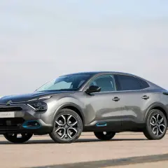 Szary Citroen C4X z niebieskimi akcentami stoi na betonowym placu.