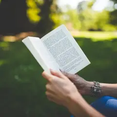 Ciało kobiety, mądrość kobiety. Kobieta czyta książkę w parku, pogrążona w lekturze.