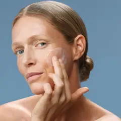 Donna applica crema viso. Scopri a cosa serve il peptide per una pelle radiosa e giovane.