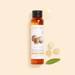 Flacon d'huile de macadamia, ses bienfaits pour la peau sont nombreux. Noix et feuille à proximité.
