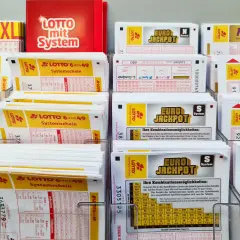 Stojaki z kuponami lotto, w tym Eurojackpot, Lotto 6 aus 49 i Keno.