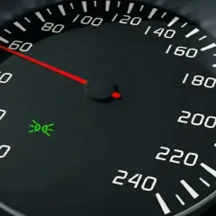 Cruscotto auto: tachimetro segna 60, spia luci posizione accesa.