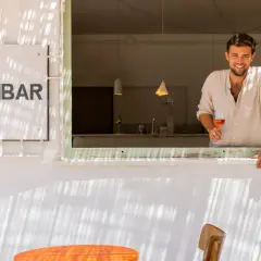 Hombre sonriente con copa de vino rosado en Samamabar, un lugar ideal para comer en Rodalquilar.