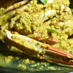 Krab w żółtym sosie curry na czarnym talerzu.