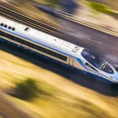 Srebrno-niebieski pociąg PKP Intercity mknie po torach, ukazując imponującą prędkość pociągu.