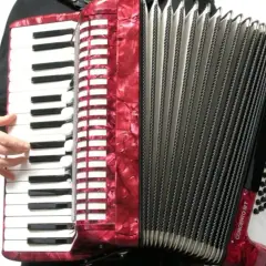 Czerwony akordeon instrument, z klawiaturą i miechem, gotowy do gry.