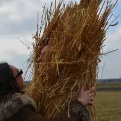 Kobieta w futrzanym płaszczu przytula się do słomianego chochoła, jak wygląda chochoł z wesela.