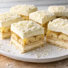 Pyszna krajanka bananowa z kremem i galaretką, posypana wiórkami białej czekolady.