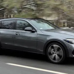 Szary Mercedes All-Terrain z napędem 4matic pędzi po drodze, zaśnieżone drzewa w tle.