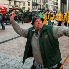 Rolnik w zielonej kamizelce z hasłem "KWS Sugar Club" protestuje, trzymając jajko i laskę.