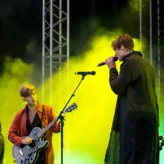 Mando Diao konsert med rök och ljus. Sångaren med mikrofon och gitarristen i röd jacka.