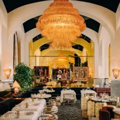 Un restaurant romantique à Paris, avec un lustre orange spectaculaire, des banquettes sombres, des tables dressées et des œuvres d'art.