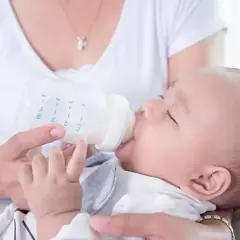 Mama karmi dziecko mlekiem z butelki. Dziecko powinno pić mleko, dopóki nie zacznie jeść stałych pokarmów.