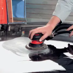 Mani esperte utilizzano una levigatrice per stuccare auto, preparando la carrozzeria per una finitura impeccabile.