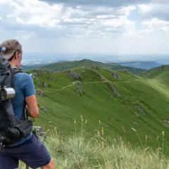 Randonnée Cantal 2 jours : un randonneur admire le paysage verdoyant des monts du Cantal, prêt pour son aventure.