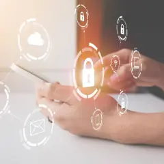 Manos sujetando un teléfono con iconos de seguridad y dispositivos de almacenamiento conectados, simbolizando la protección de datos.