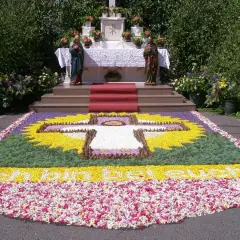 Ein Blumenteppich mit Kreuz und Schriftzug "Ich bin das Brot" erinnert an den Fronleichnam Ursprung.