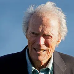 Clint Eastwood heute, mit seinem charakteristischen Lächeln und zerzaust grauem Haar, blickt in die Kamera.