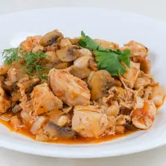 Pyszna potrawka z kurczaka z pieczarkami i fasolą w sosie pomidorowym, udekorowana koperkiem i natką pietruszki.
