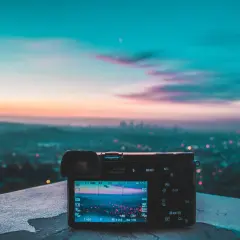 Aparat fotograficzny na tle miejskiego krajobrazu o zachodzie słońca. Wspaniałe światło w fotografii uchwycone w kadrze.
