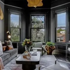 Elegancki salon w stylu wiktoriańskim. Ciemne ściany, ozdobne okna i stylowe meble tworzą przytulną atmosferę.