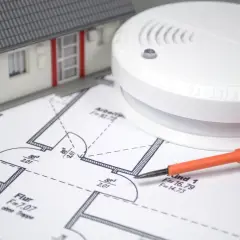 Hausplan mit Rauchmelder und Schraubendreher. Hier erfahren Sie, wo ein Feuermelder Pflicht ist.