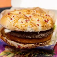Apetyczny zestaw drwala kcal: soczysty burger z podwójną wołowiną, chrupiącym plackiem ziemniaczanym i bułką posypaną serem i kawałkami boczku.