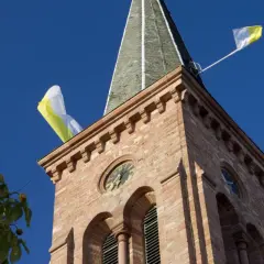Kirchturm mit Fahnen im Wind, ein Zeichen, dass die Kirchweih gefeiert wird.