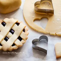Pasta frolla pronta per essere infornata. La temperatura di cottura è fondamentale per ottenere un risultato perfetto. Cuoricini di frolla e crostata con marmellata.