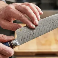 Hände reinigen ein Damastmesser, um Rost von Messer entfernen. Das Muster auf der Klinge ist deutlich sichtbar.