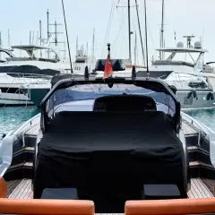 Un porto pieno di yacht di lusso, pronti per il trasporto barche. La vista è dal retro di un gommone con sedili in pelle arancione.