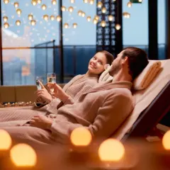 Para relaksująca w spa: para w szlafrokach z kieliszkami szampana, przy świecach.