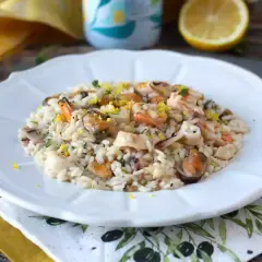 Delicioso risotto de marisco con mejillones, gambas y calamares, adornado con ralladura de limón y perejil fresco.