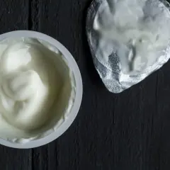 Gęsty, biały jogurt w kubeczku, obok srebrna folia. To skyr, islandzki przysmak bogaty w białko.