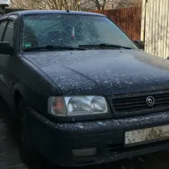Ciemny samochód pokryty śniegiem i błotem, wyglądający jakby groził mu mandat za brudne auto.